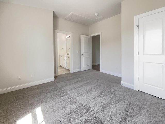 unfurnished bedroom with carpet floors, baseboards, attic access, and connected bathroom