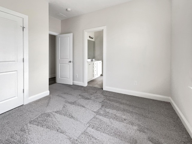 unfurnished bedroom featuring baseboards, connected bathroom, and carpet