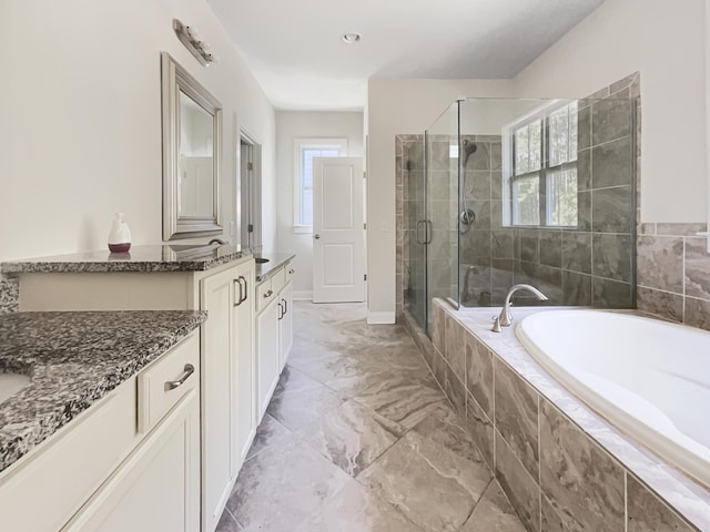 full bath with a garden tub, a stall shower, two vanities, baseboards, and marble finish floor