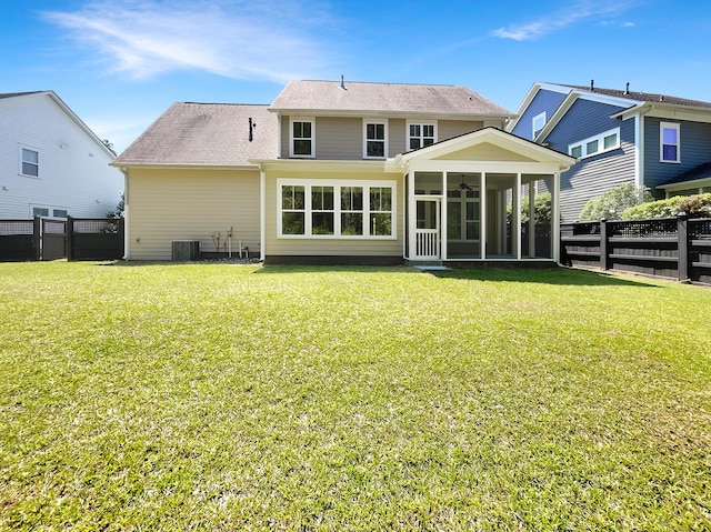 rear view of house with a yard, ceiling fan, a fenced backyard, and a sunroom