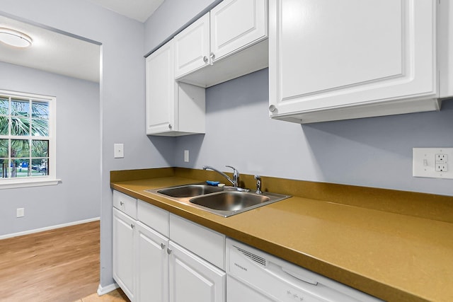 kitchen with white cabinetry, a sink, light wood-style flooring, and baseboards