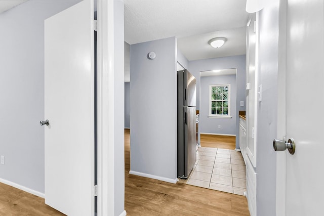 hall featuring light wood-style floors and baseboards