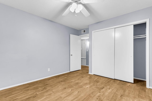 unfurnished bedroom featuring baseboards, a closet, visible vents, and wood finished floors