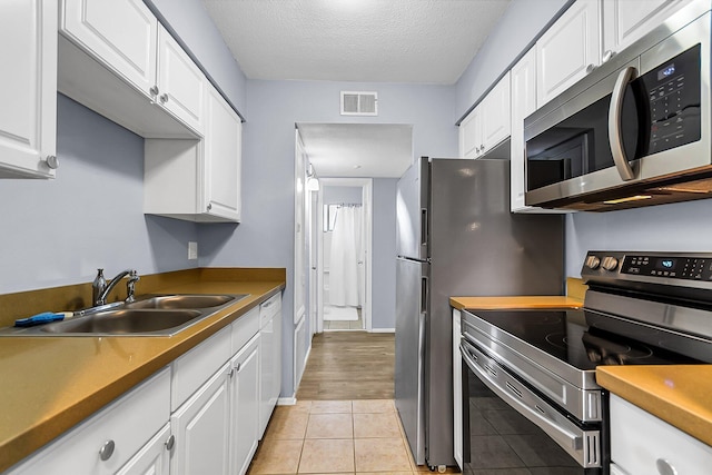 kitchen featuring light tile patterned floors, visible vents, stainless steel appliances, white cabinetry, and a sink