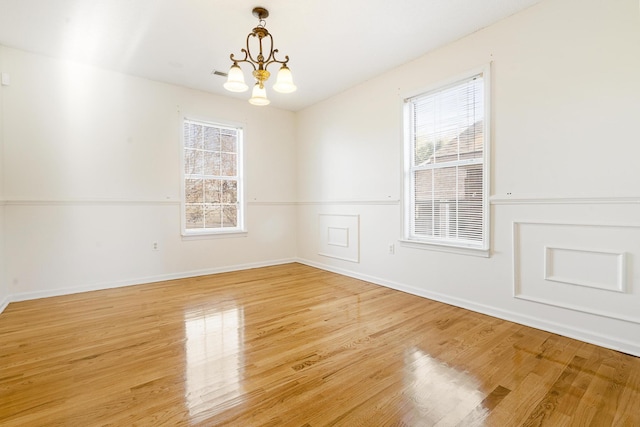 empty room with a notable chandelier and wood-type flooring