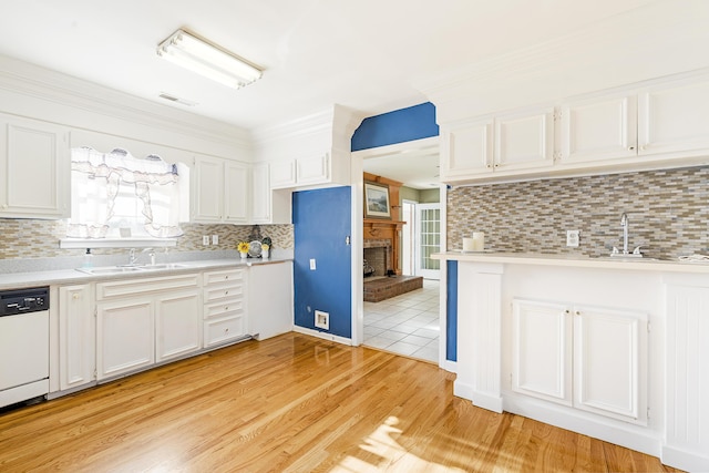 kitchen featuring backsplash, white dishwasher, sink, light hardwood / wood-style flooring, and white cabinetry