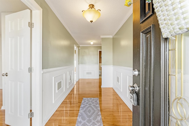 hall with hardwood / wood-style flooring, ornamental molding, and a textured ceiling