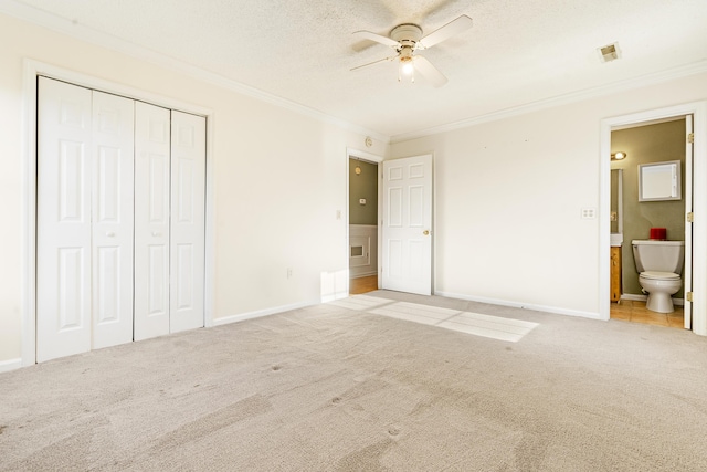 unfurnished bedroom with ensuite bath, ceiling fan, light colored carpet, a closet, and ornamental molding