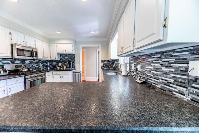 409 Santee Dr, Santee, SC 29142 - kitchen with stainless steel appliances, dark countertops, a sink, white cabinetry, and decorative backsplash
