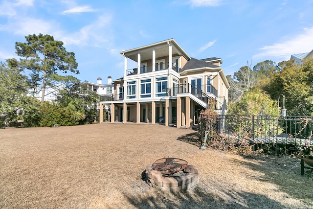 back of property featuring a fire pit, a balcony, and a wooden deck