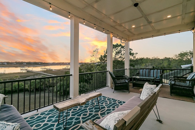 balcony at dusk with a water view and an outdoor hangout area