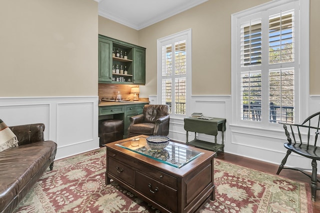 living room featuring wood-type flooring, indoor bar, and ornamental molding