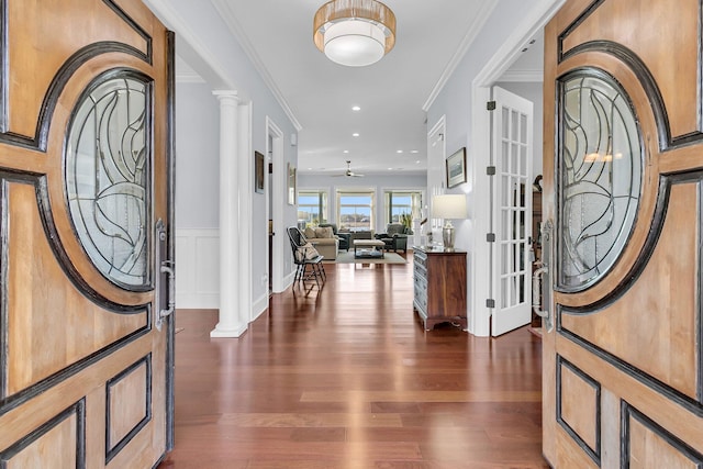 foyer featuring decorative columns, crown molding, dark hardwood / wood-style flooring, and ceiling fan