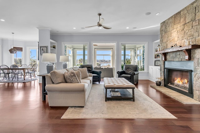 living room featuring crown molding, ceiling fan, dark hardwood / wood-style floors, built in features, and a fireplace