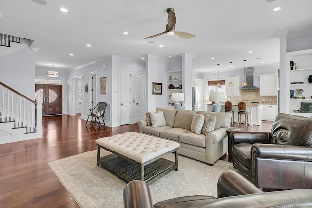 living room featuring wood-type flooring, built in features, ceiling fan, and crown molding