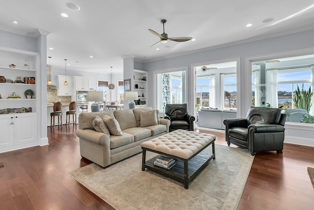 living room with built in shelves, hardwood / wood-style flooring, ceiling fan, and ornamental molding