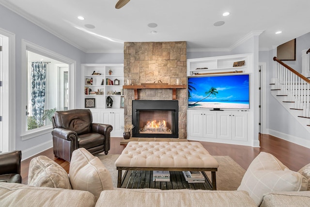 living room with hardwood / wood-style flooring, a stone fireplace, and ornamental molding