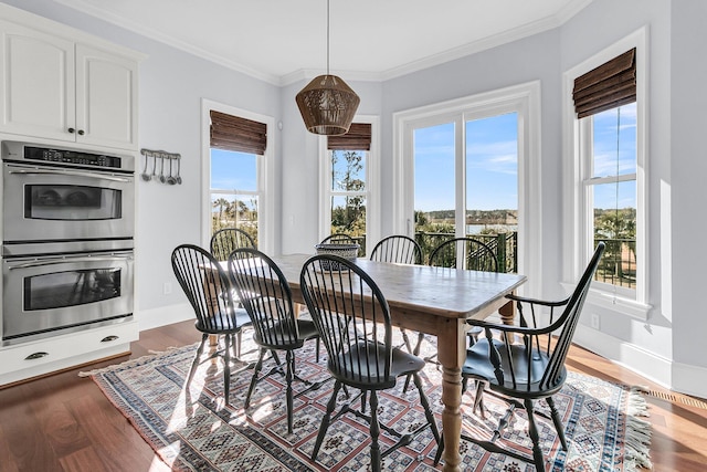 dining space with crown molding, plenty of natural light, and dark wood-type flooring