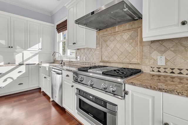 kitchen with light stone countertops, ventilation hood, backsplash, white cabinets, and appliances with stainless steel finishes