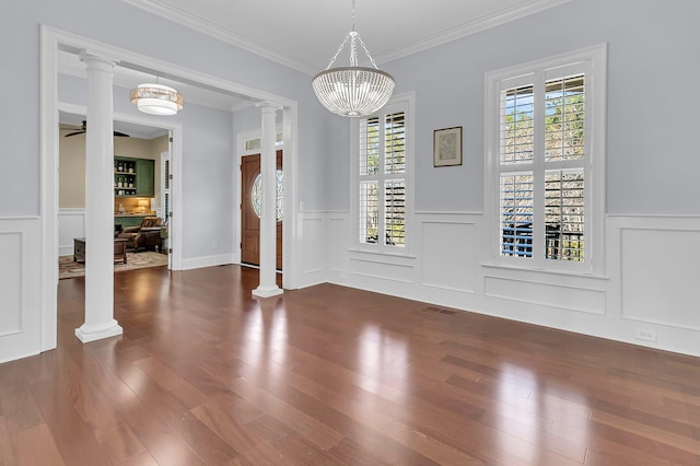 unfurnished dining area with ornamental molding, decorative columns, and a notable chandelier