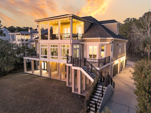 back house at dusk featuring a balcony and a patio