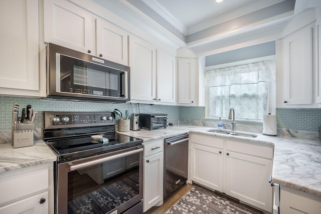 2177 Gulf Dr, Mount Pleasant, SC 29464 - kitchen featuring appliances with stainless steel finishes, a sink, ornamental molding, white cabinetry, and tasteful backsplash