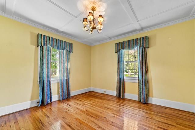 spare room with coffered ceiling, hardwood / wood-style floors, a notable chandelier, and ornamental molding