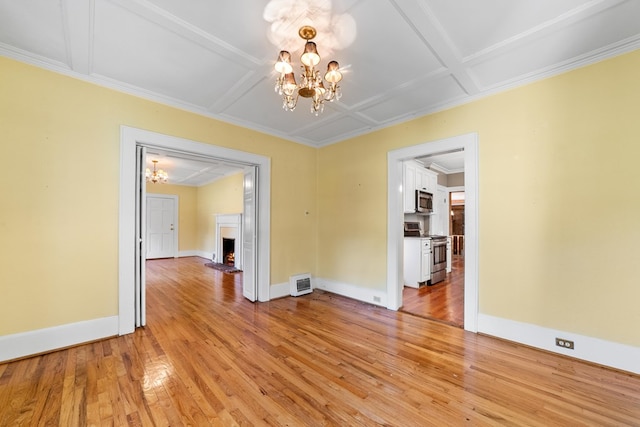 unfurnished dining area featuring coffered ceiling, an inviting chandelier, light wood-type flooring, and crown molding