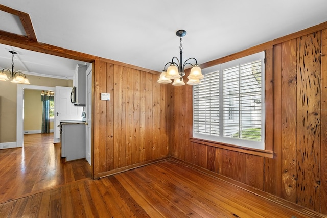 unfurnished dining area with a wealth of natural light, dark wood-type flooring, and a chandelier