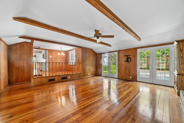 unfurnished living room featuring french doors, vaulted ceiling with beams, hardwood / wood-style flooring, and wooden walls