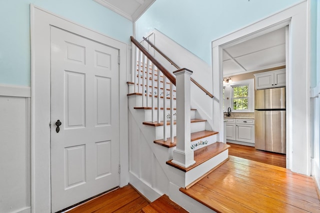 stairs with crown molding and hardwood / wood-style floors