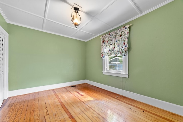 empty room with crown molding, hardwood / wood-style floors, and coffered ceiling