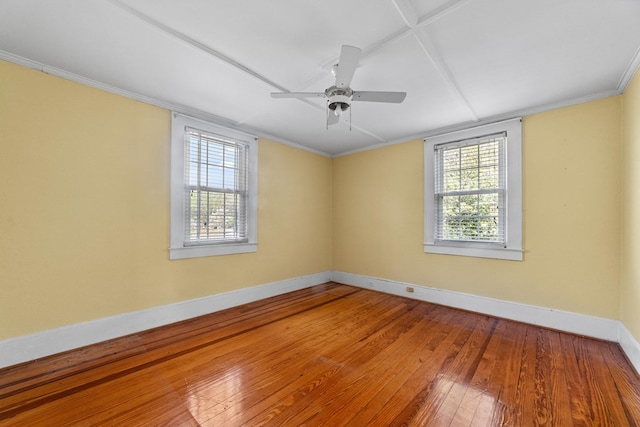 spare room featuring wood-type flooring, crown molding, a wealth of natural light, and ceiling fan