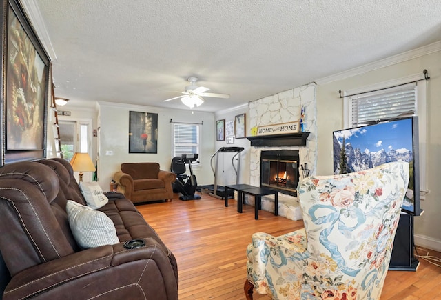 living room with a stone fireplace, hardwood / wood-style flooring, crown molding, and a textured ceiling