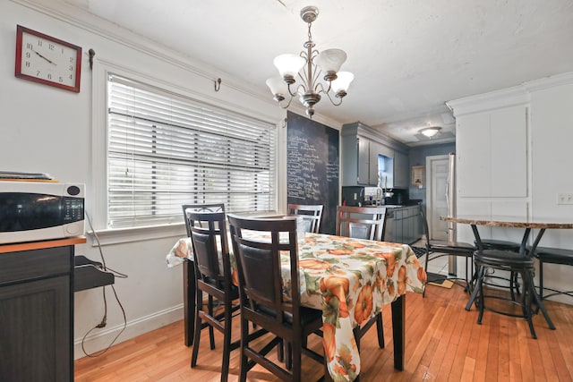 dining room featuring light hardwood / wood-style floors, ornamental molding, an inviting chandelier, and sink