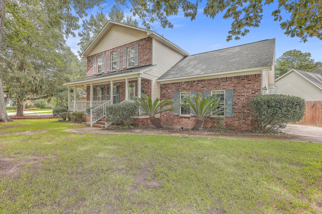 view of front property featuring covered porch and a front yard