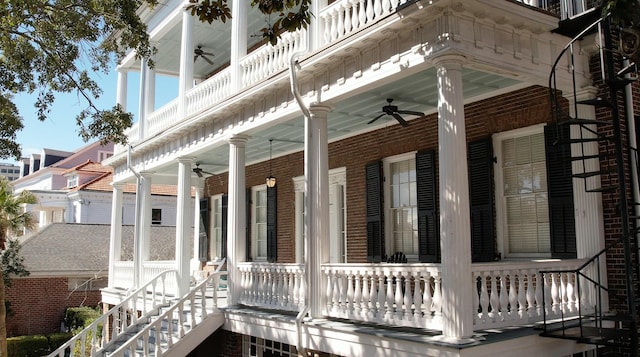 view of side of property featuring covered porch, ceiling fan, and brick siding