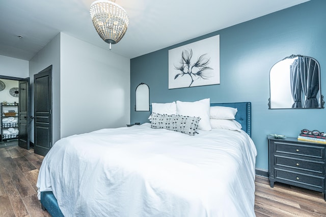 bedroom with dark hardwood / wood-style flooring and an inviting chandelier