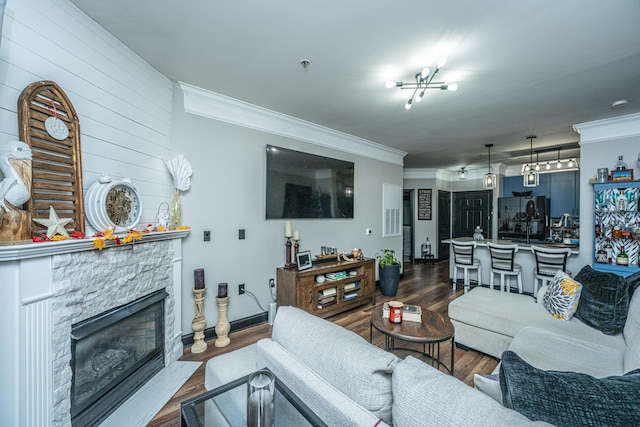 living room with hardwood / wood-style floors, a stone fireplace, and ornamental molding