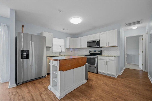 kitchen with white cabinetry, visible vents, stainless steel appliances, and wood finished floors