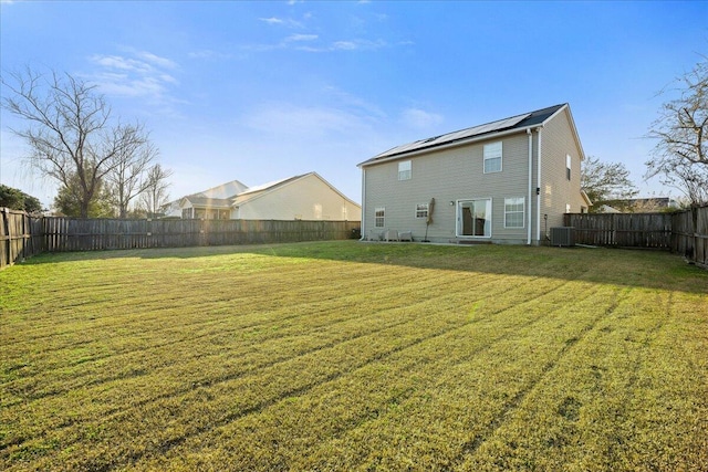 back of house with a yard, central AC, solar panels, and a fenced backyard