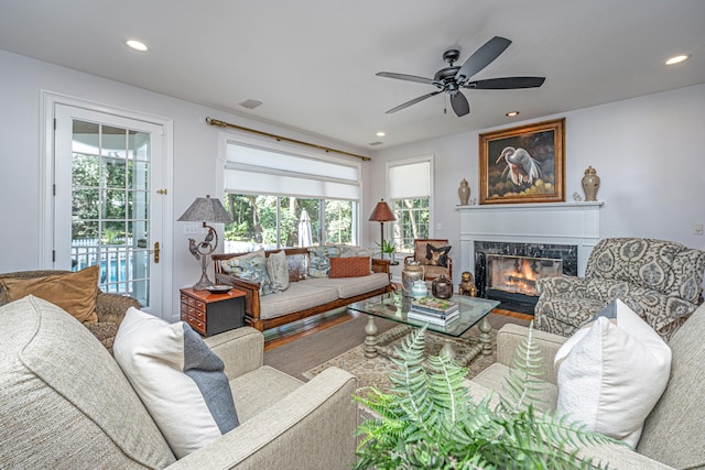 living room with a tiled fireplace and ceiling fan