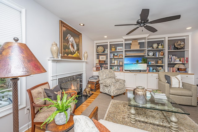 living room with ceiling fan, hardwood / wood-style flooring, a fireplace, and built in shelves