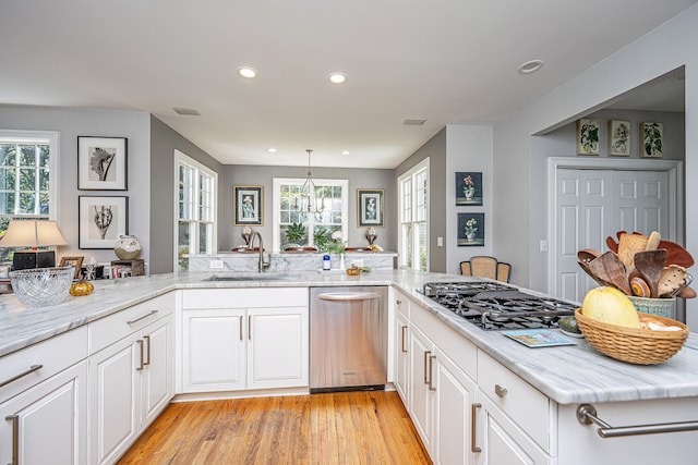 kitchen featuring white cabinets, kitchen peninsula, stainless steel appliances, light hardwood / wood-style flooring, and sink