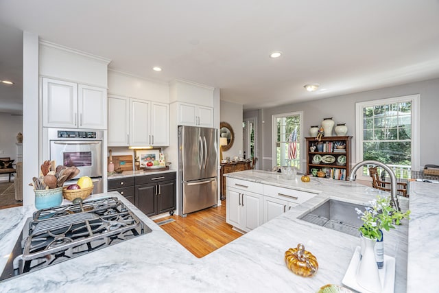 kitchen featuring light stone counters, light hardwood / wood-style floors, sink, white cabinets, and stainless steel appliances