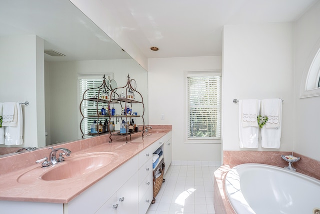 bathroom featuring tiled tub, vanity, tile patterned flooring, and a wealth of natural light