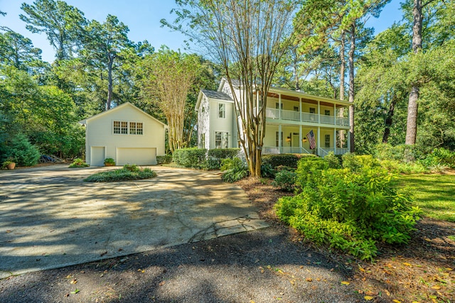 view of front of property with a balcony, a garage, and an outbuilding