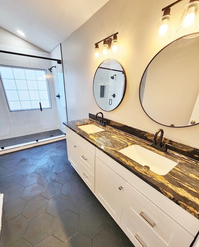 bathroom with tile patterned floors, vanity, a tile shower, and vaulted ceiling