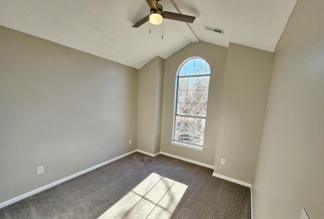 spare room with ceiling fan, dark carpet, and vaulted ceiling