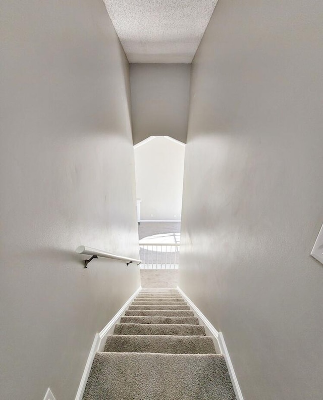 stairs featuring a textured ceiling